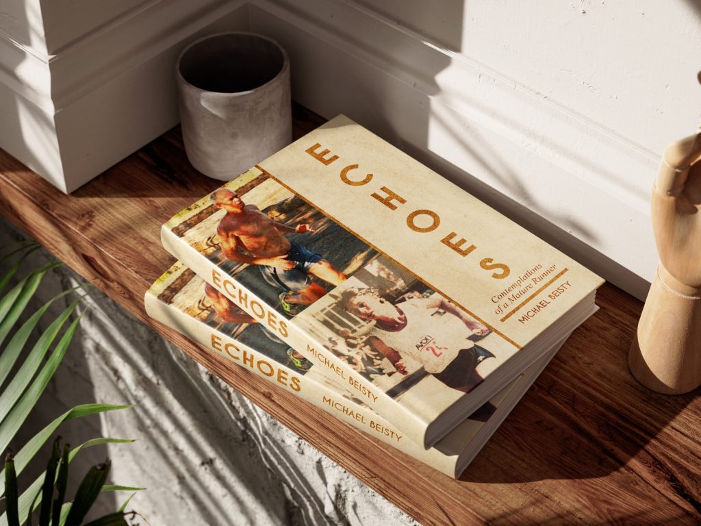 A hand rests on a book on a table, accompanied by a small green plant nearby.