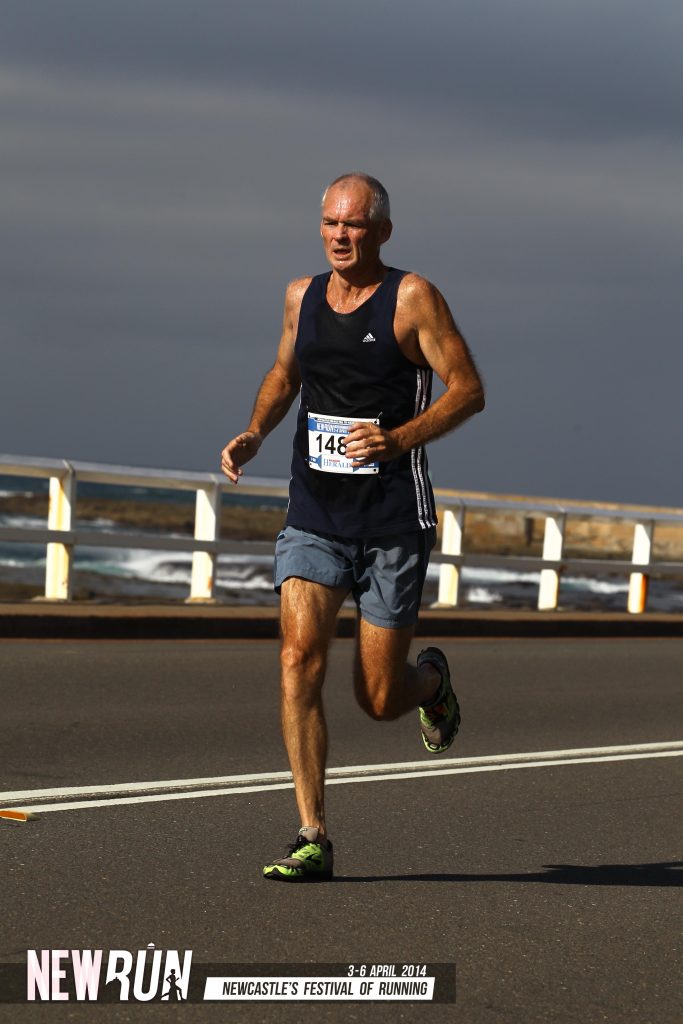 A man sprinting along a road during a marathon, showcasing determination and athleticism.